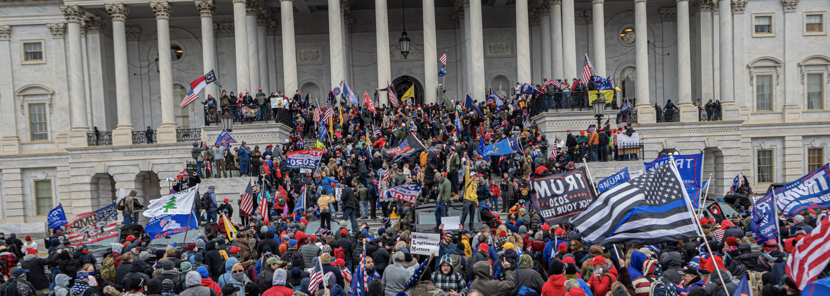 Insurrectionists storm the Capitol Building on January 6, 2021. They waive Trump flags, American flags, police flags, and other white supremacy flags.