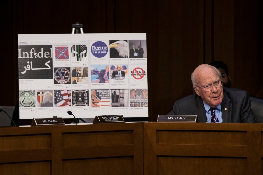 Sen. Patrick Leahy sits in front of a poster with examples of Russian-created Facebook pages